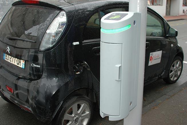 Une citadine électrique Citroën C-Zero stationnée devant l’un des trois premières bornes de recharge CityCharge