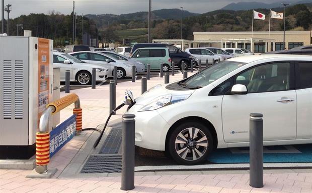 Une Nissan LEAF électrique branchée sur une borne de recharge rapide installée sur une aire d’autoroute au Japon