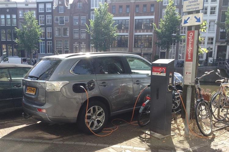 A Amsterdam, un crossover Mitsubishi Outlander PHEV à motorisation hybride rechargeable branché sur une borne de recharge publique EV-Box