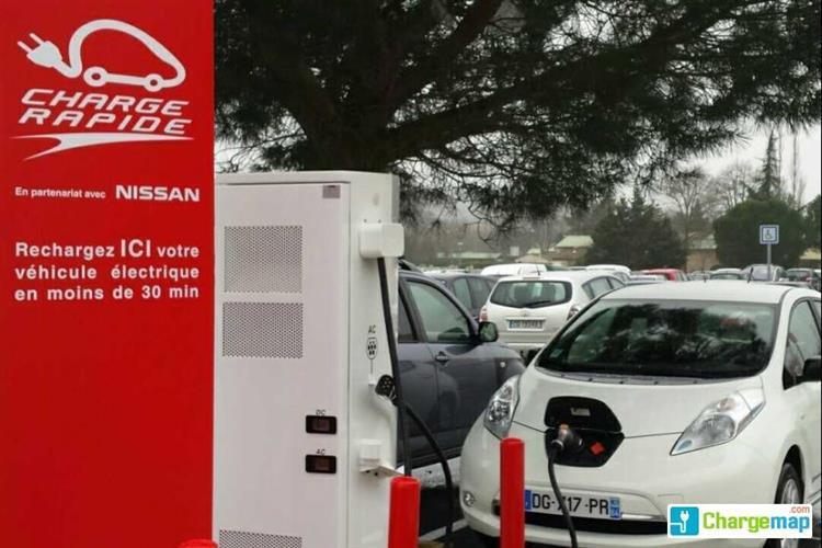 Une compacte électrique Nissan LEAF branchée sur une borne de recharge rapide dans un centre commercial Auchan